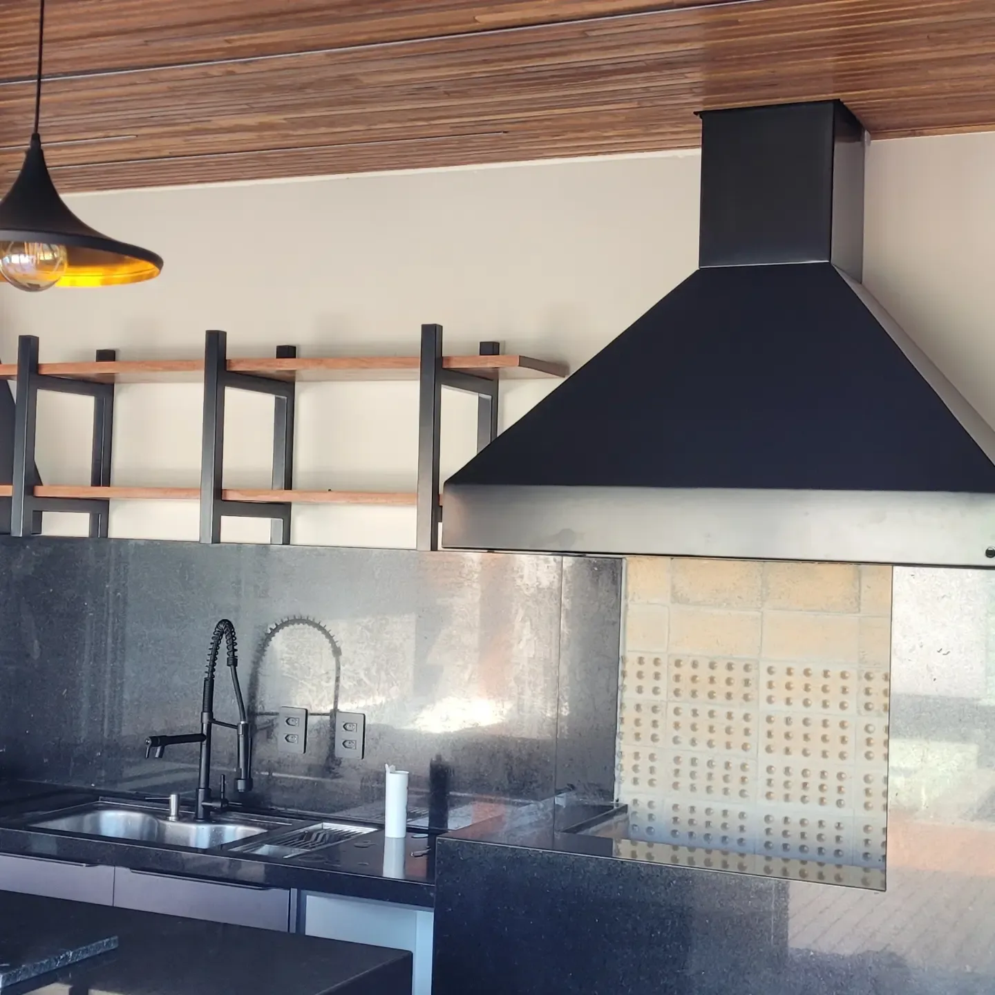 Coifa em inox pintado e estantes com estrutura metálica em espaço gourmet residencial